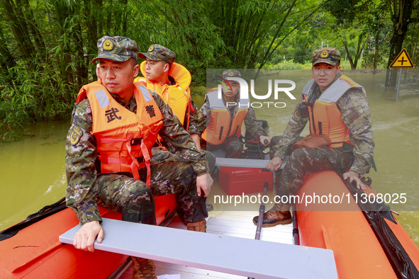 Armed police officers and soldiers are using rubber boats to search for people trapped in Shilong village, Gongchuan Township, Dahua County,...