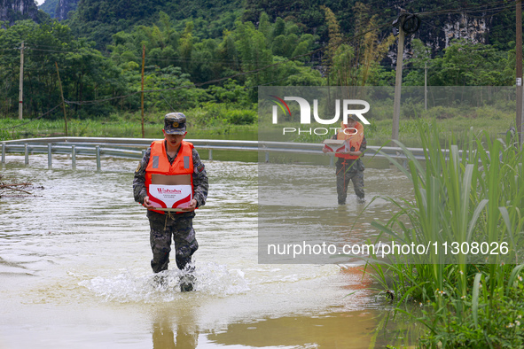 Armed police officers are transferring supplies at Shilong Village, Gongchuan Township, Dahua County, in Hechi, China, on June 5, 2024. 