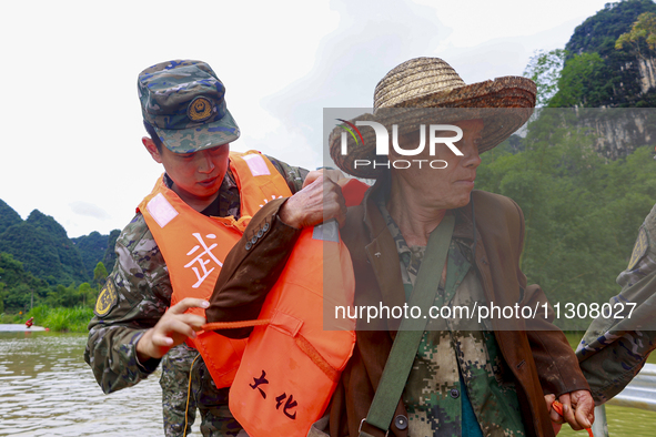 Armed police officers are putting life jackets on an elderly man at Shilong Village, Gongchuan Township, Dahua County, in Hechi, China, on J...