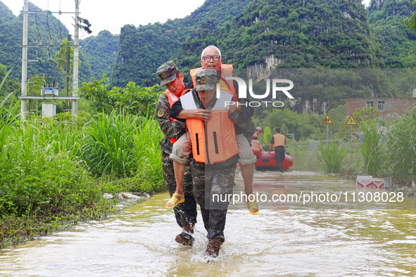 Armed police officers and men with their backs are crossing a wading road in Shilong Village, Gongchuan Township, Dahua County, Hechi city,...