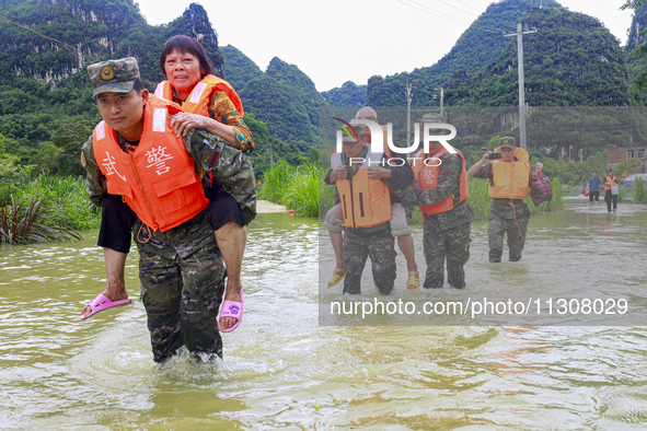 Armed police officers and men with their backs are crossing a wading road in Shilong Village, Gongchuan Township, Dahua County, Hechi city,...