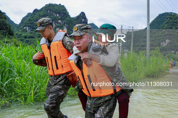 Armed police officers and men with their backs are crossing a wading road in Shilong Village, Gongchuan Township, Dahua County, Hechi city,...