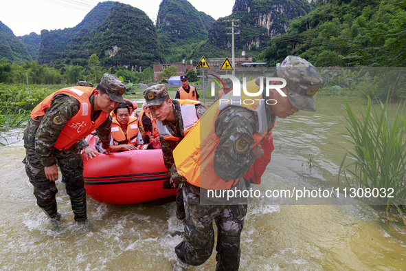 Armed police officers and soldiers are using rubber boats to move victims in Shilong Village, Gongchuan Township, Dahua County, Hechi city,...