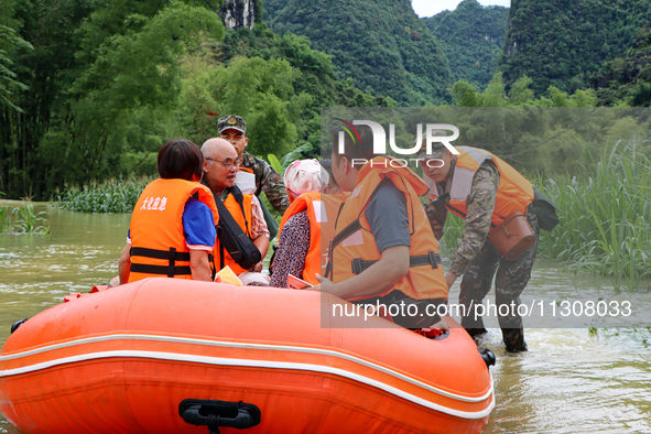 Armed police officers and soldiers are using rubber boats to move victims in Shilong Village, Gongchuan Township, Dahua County, Hechi city,...