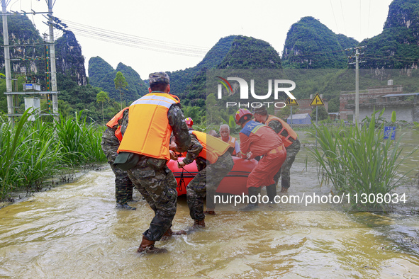 Armed police officers and soldiers are using rubber boats to move victims in Shilong Village, Gongchuan Township, Dahua County, Hechi city,...