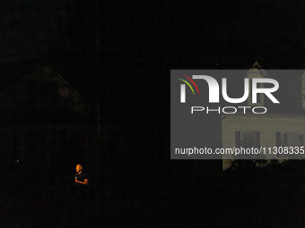 A news reporter is illuminated by a camera light in a dark Gaithersburg, Maryland neighborhood on June 5, 2024, after a tornado swept throug...