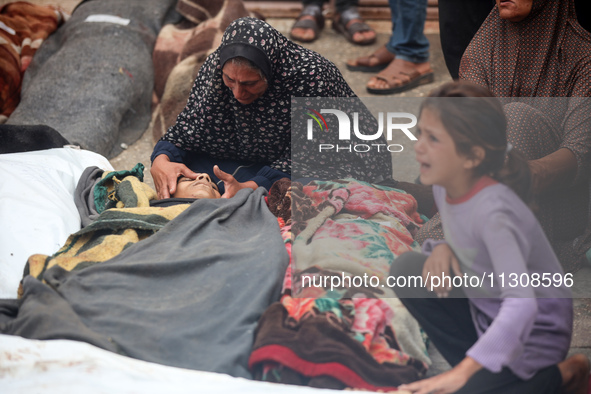 Relatives are mourning over the bodies of people killed in an Israeli airstrike at a UN school housing displaced Palestinians in Nuseirat, a...