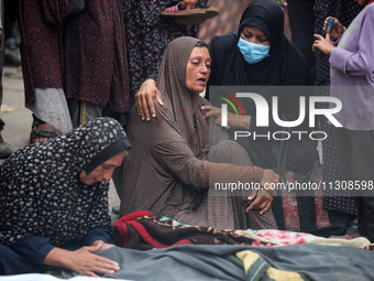 Relatives are mourning over the bodies of people killed in an Israeli airstrike at a UN school housing displaced Palestinians in Nuseirat, a...