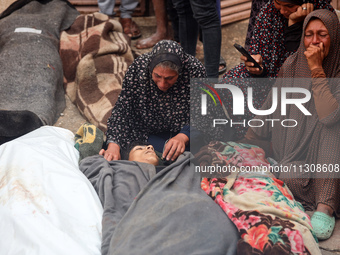 Relatives are mourning over the bodies of people killed in an Israeli airstrike at a UN school housing displaced Palestinians in Nuseirat, a...