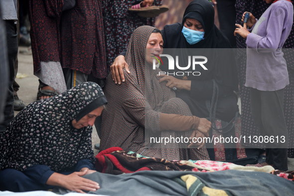 Relatives are mourning over the bodies of people killed in an Israeli airstrike at a UN school housing displaced Palestinians in Nuseirat, a...