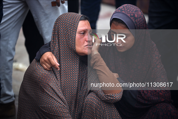 Relatives are mourning over the bodies of people killed in an Israeli airstrike at a UN school housing displaced Palestinians in Nuseirat, a...