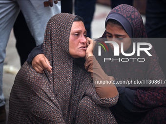 Relatives are mourning over the bodies of people killed in an Israeli airstrike at a UN school housing displaced Palestinians in Nuseirat, a...