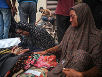 Relatives are mourning over the bodies of people killed in an Israeli airstrike at a UN school housing displaced Palestinians in Nuseirat, a...