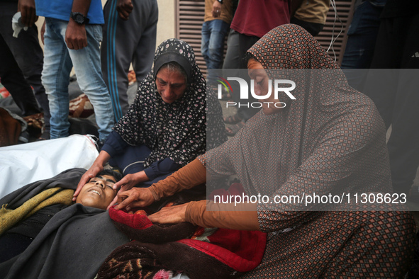 Relatives are mourning over the bodies of people killed in an Israeli airstrike at a UN school housing displaced Palestinians in Nuseirat, a...