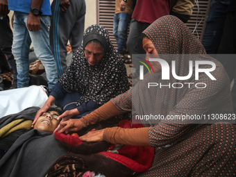 Relatives are mourning over the bodies of people killed in an Israeli airstrike at a UN school housing displaced Palestinians in Nuseirat, a...