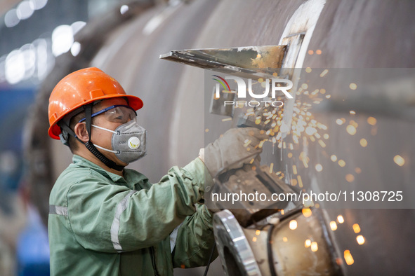 A worker is producing various types of pressure vessel equipment at a pressure vessel workshop in Nantong, Jiangsu province, China, on June...