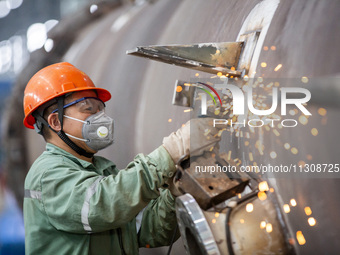 A worker is producing various types of pressure vessel equipment at a pressure vessel workshop in Nantong, Jiangsu province, China, on June...