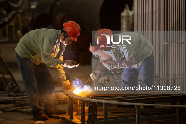 A worker is producing various types of pressure vessel equipment at a pressure vessel workshop in Nantong, Jiangsu province, China, on June...