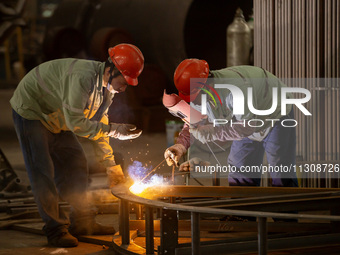 A worker is producing various types of pressure vessel equipment at a pressure vessel workshop in Nantong, Jiangsu province, China, on June...