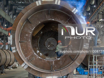 A worker is producing various types of pressure vessel equipment at a pressure vessel workshop in Nantong, Jiangsu province, China, on June...