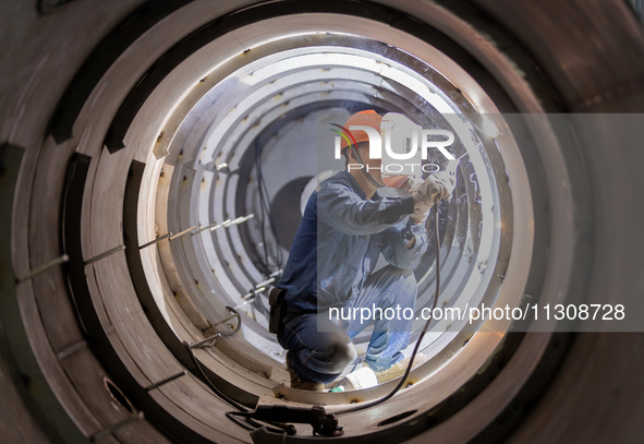 A worker is producing various types of pressure vessel equipment at a pressure vessel workshop in Nantong, Jiangsu province, China, on June...