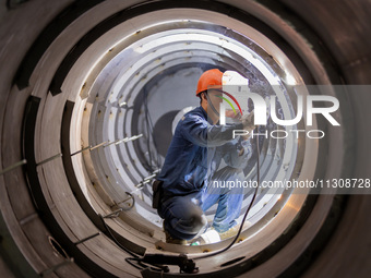 A worker is producing various types of pressure vessel equipment at a pressure vessel workshop in Nantong, Jiangsu province, China, on June...