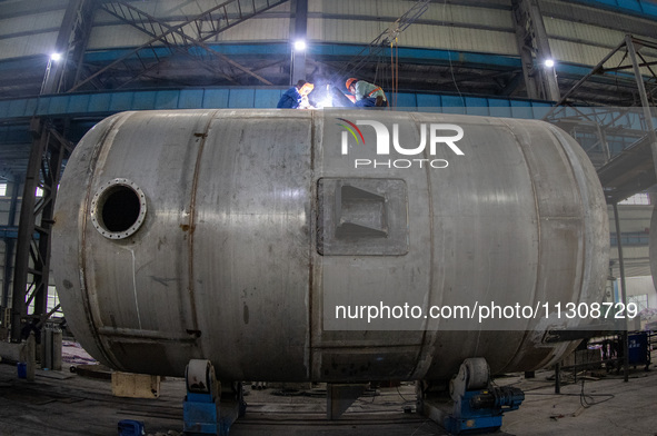 A worker is producing various types of pressure vessel equipment at a pressure vessel workshop in Nantong, Jiangsu province, China, on June...