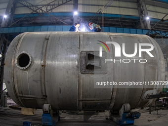 A worker is producing various types of pressure vessel equipment at a pressure vessel workshop in Nantong, Jiangsu province, China, on June...