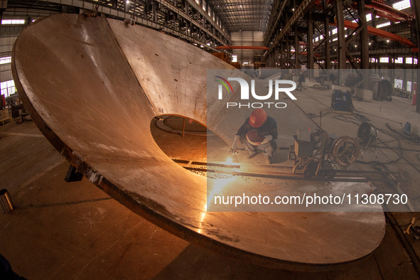 A worker is producing various types of pressure vessel equipment at a pressure vessel workshop in Nantong, Jiangsu province, China, on June...