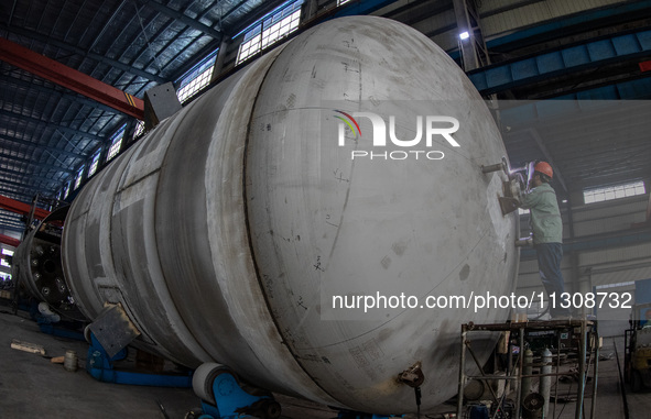 A worker is producing various types of pressure vessel equipment at a pressure vessel workshop in Nantong, Jiangsu province, China, on June...