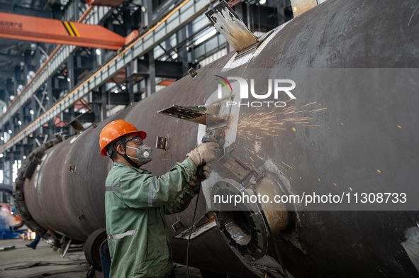 A worker is producing various types of pressure vessel equipment at a pressure vessel workshop in Nantong, Jiangsu province, China, on June...