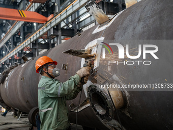 A worker is producing various types of pressure vessel equipment at a pressure vessel workshop in Nantong, Jiangsu province, China, on June...