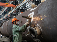 A worker is producing various types of pressure vessel equipment at a pressure vessel workshop in Nantong, Jiangsu province, China, on June...