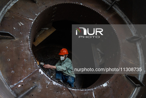 A worker is producing various types of pressure vessel equipment at a pressure vessel workshop in Nantong, Jiangsu province, China, on June...