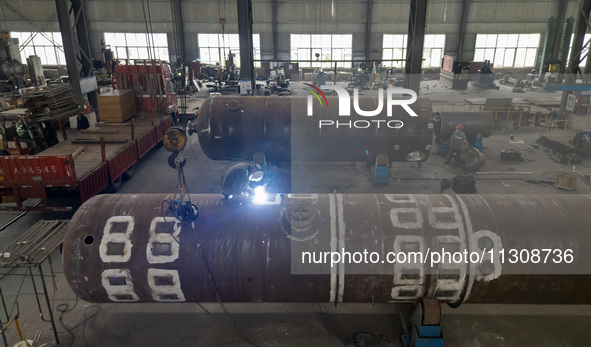 A worker is producing various types of pressure vessel equipment at a pressure vessel workshop in Nantong, Jiangsu province, China, on June...