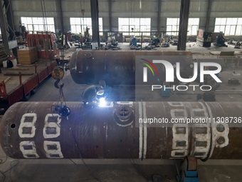 A worker is producing various types of pressure vessel equipment at a pressure vessel workshop in Nantong, Jiangsu province, China, on June...