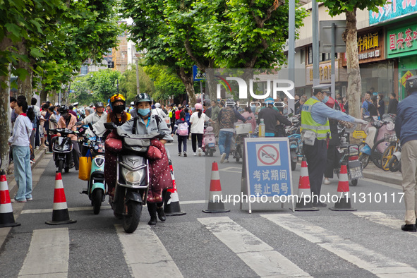 Police are reminding people to use electric bicycles at a crossroads outside a gaokao test center in Shanghai, China, on June 7, 2024. 