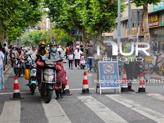 Police are reminding people to use electric bicycles at a crossroads outside a gaokao test center in Shanghai, China, on June 7, 2024. (