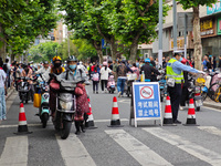 Police are reminding people to use electric bicycles at a crossroads outside a gaokao test center in Shanghai, China, on June 7, 2024. (