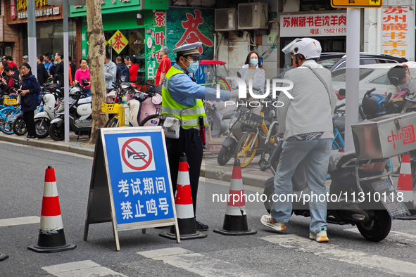 Police are reminding people to use electric bicycles at a crossroads outside a gaokao test center in Shanghai, China, on June 7, 2024. 