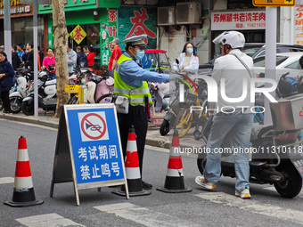 Police are reminding people to use electric bicycles at a crossroads outside a gaokao test center in Shanghai, China, on June 7, 2024. (