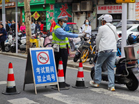 Police are reminding people to use electric bicycles at a crossroads outside a gaokao test center in Shanghai, China, on June 7, 2024. (