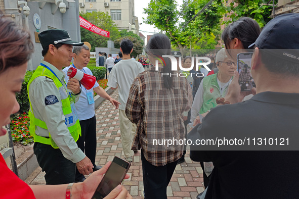 Volunteers are maintaining order as students are entering a test room to take part in the National college entrance examination in Shanghai,...