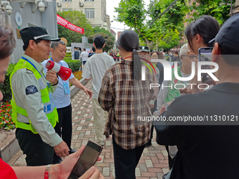 Volunteers are maintaining order as students are entering a test room to take part in the National college entrance examination in Shanghai,...