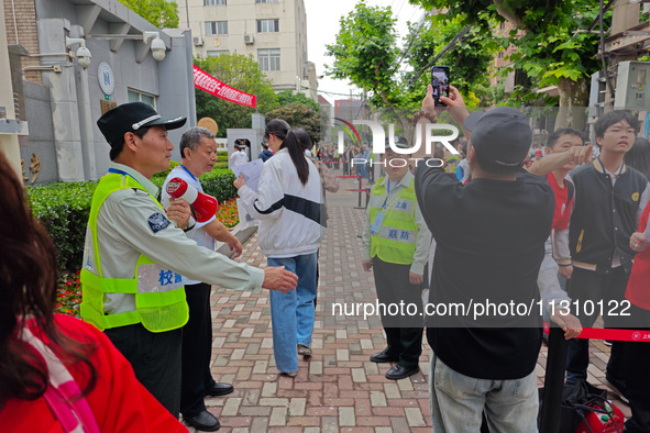 Volunteers are maintaining order as students are entering a test room to take part in the National college entrance examination in Shanghai,...