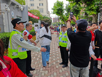 Volunteers are maintaining order as students are entering a test room to take part in the National college entrance examination in Shanghai,...