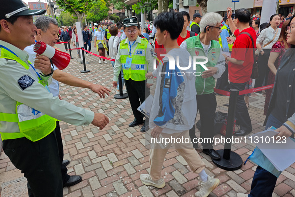 Volunteers are maintaining order as students are entering a test room to take part in the National college entrance examination in Shanghai,...