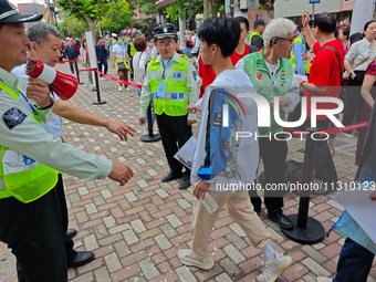 Volunteers are maintaining order as students are entering a test room to take part in the National college entrance examination in Shanghai,...