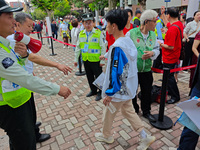 Volunteers are maintaining order as students are entering a test room to take part in the National college entrance examination in Shanghai,...