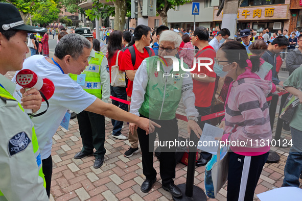 Volunteers are maintaining order as students are entering a test room to take part in the National college entrance examination in Shanghai,...